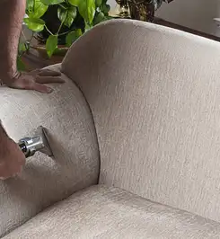 Professional upholstery cleaner deep-cleaning a fabric sofa with a handheld extraction tool and hose San Antonio, TX.